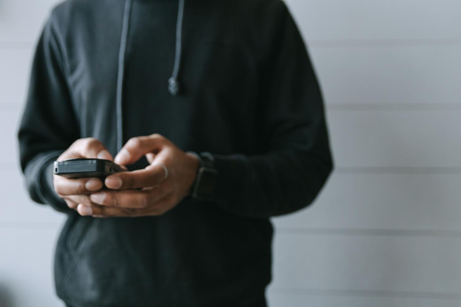 Primer plano de manos operando un teléfono móvil, ilustrando la configuración de ajustes de privacidad en WhatsApp.