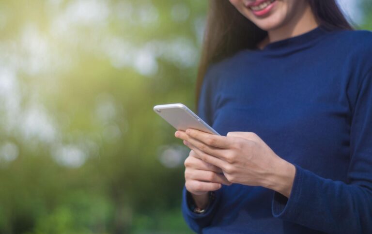 Mujer utilizando un smartphone al aire libre, representando la simplicidad de usar trucos de WhatsApp.