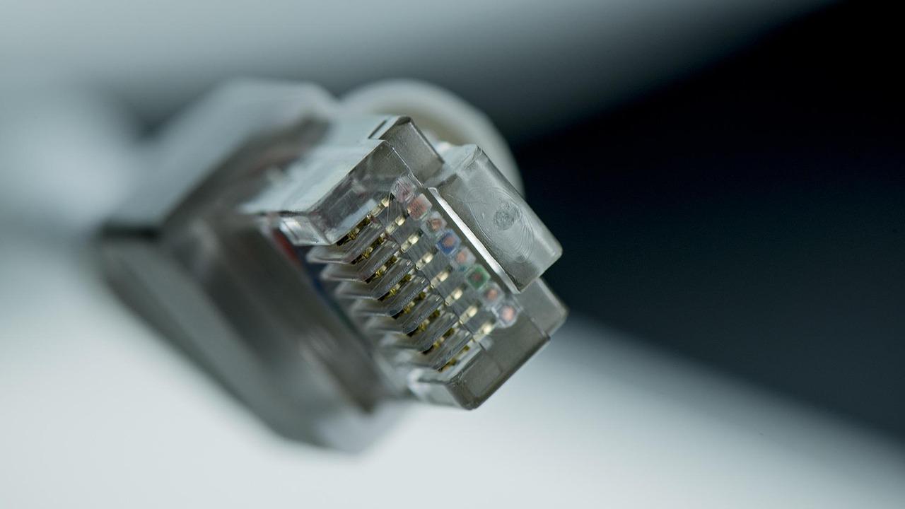 Fotografía macro detallada de un conector RJ45 mostrando los pines dorados y el cable.