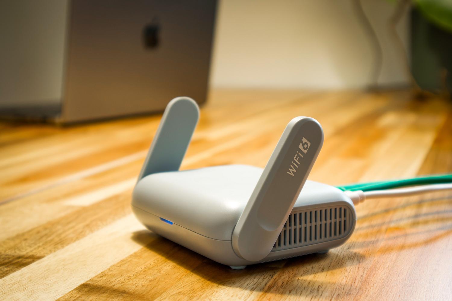 Router WiFi moderno colocado sobre un escritorio de madera en un entorno luminoso, ejemplificando la ubicación ideal a media altura.