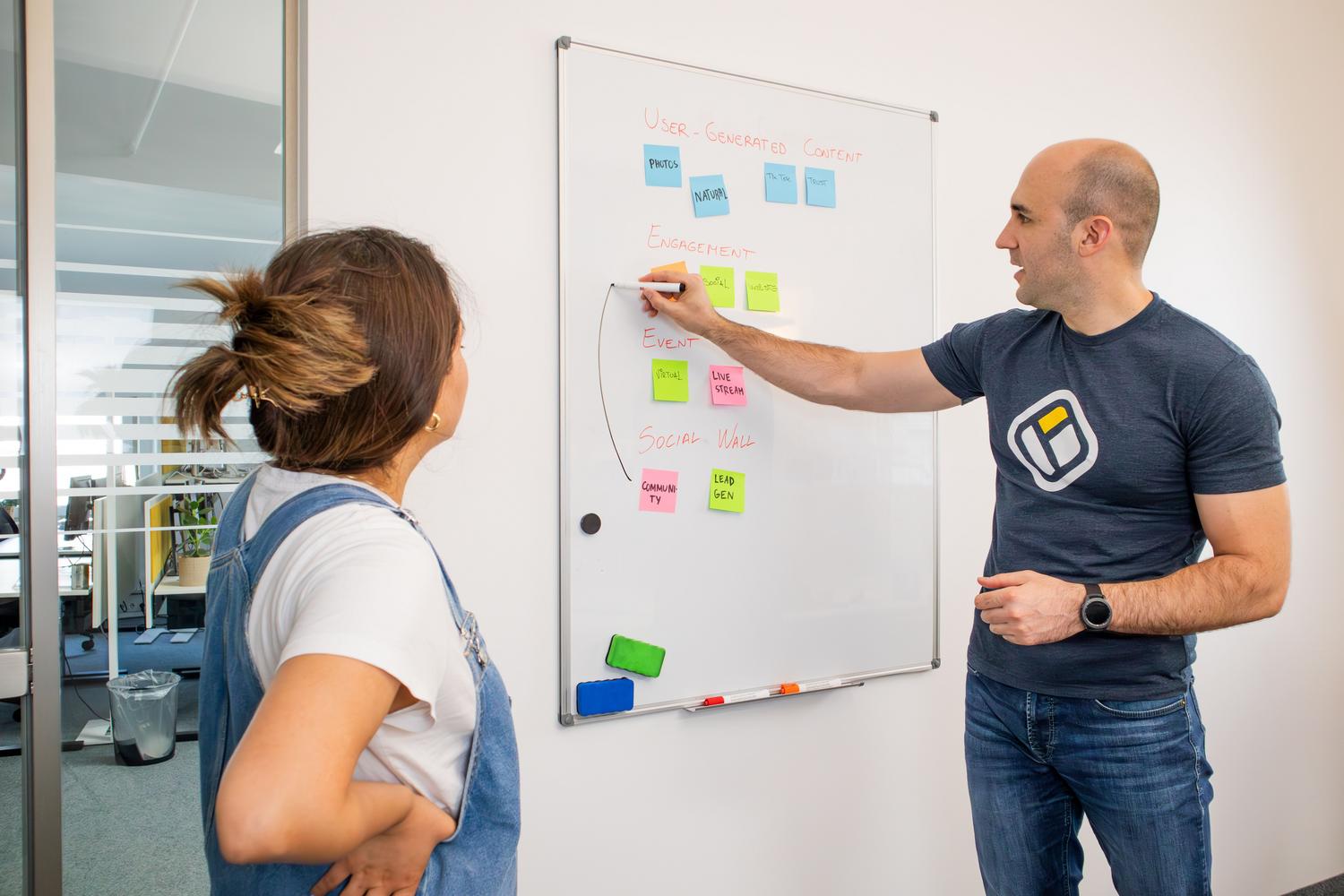 Dos profesionales realizando una sesión de brainstorming en una pizarra blanca para definir la estrategia de un proyecto.