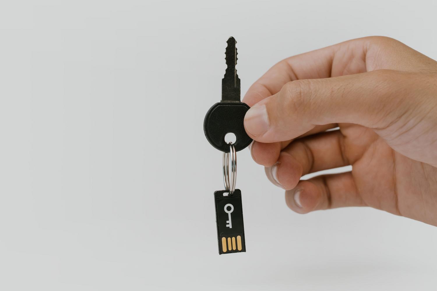 Primer plano de una mano sosteniendo una llave de seguridad USB FIDO2 para blindar el acceso a cuentas digitales.