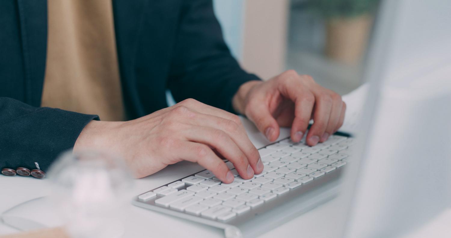 Primer plano de manos escribiendo en un teclado blanco, representando la configuración técnica y edición del registro de Windows.