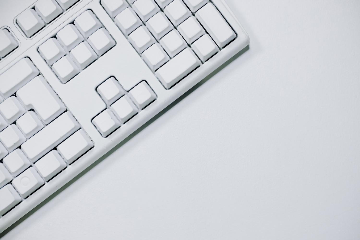 Teclado blanco minimalista sobre fondo blanco, simbolizando el rendimiento y la limpieza del sistema operativo.