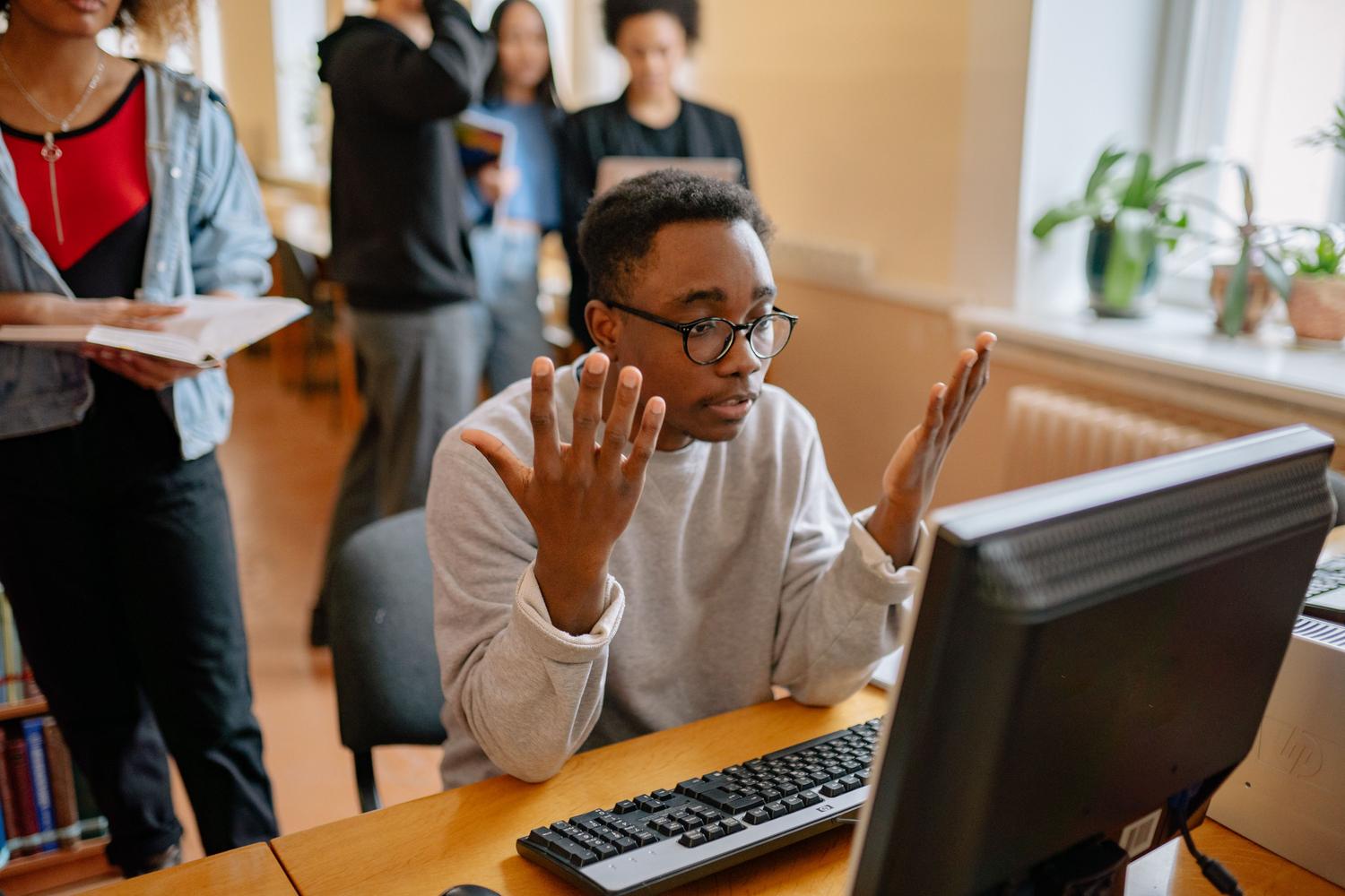 Hombre confundido mirando la pantalla de su ordenador mientras intenta solucionar un error técnico