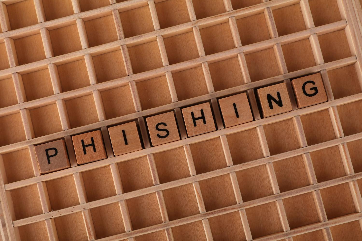 Letras de madera formando la palabra 'Phishing', representando visualmente la técnica de engaño utilizada en las estafas a creadores.