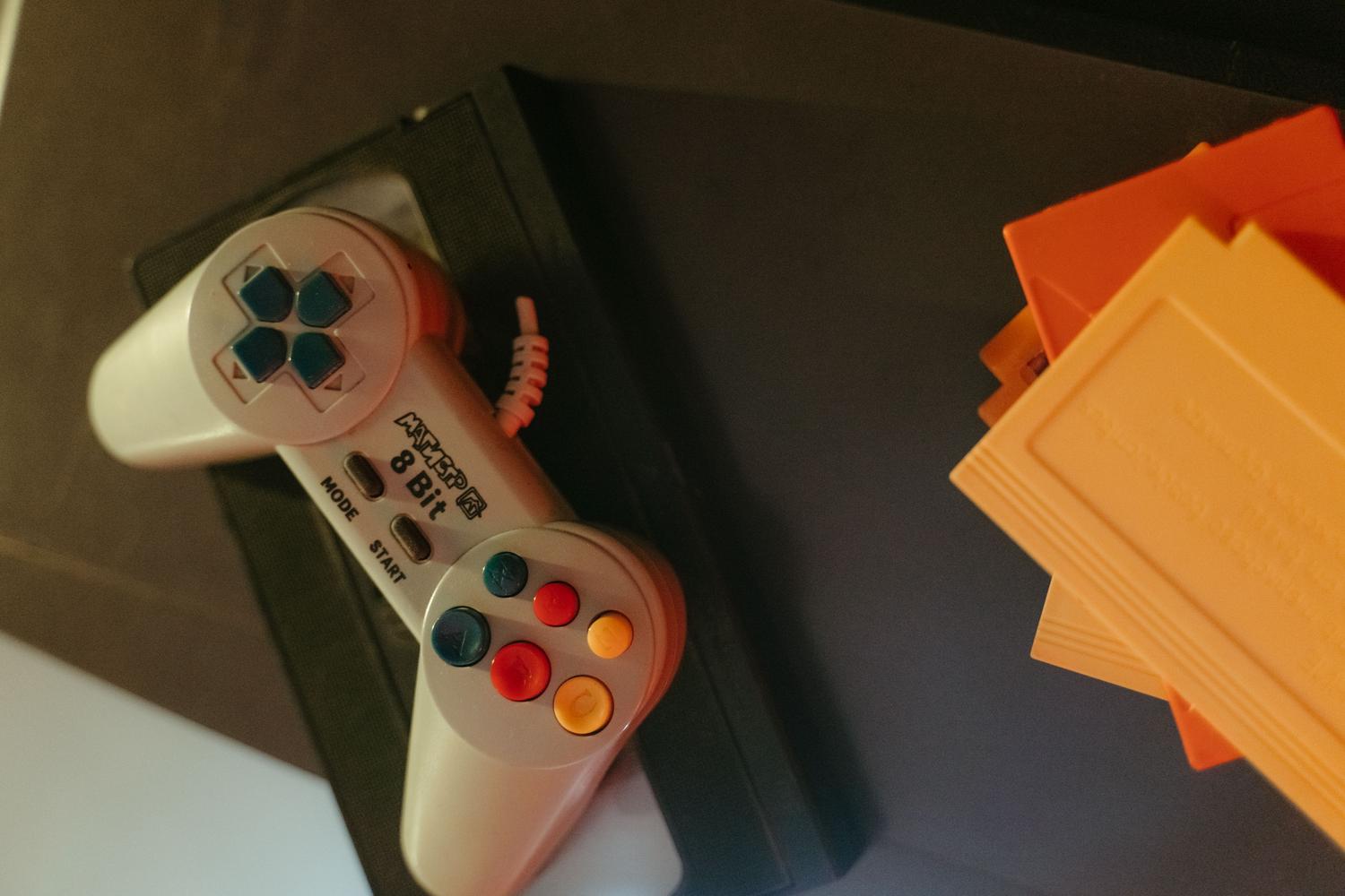 Colección de cartuchos de juegos retro y un mando clásico, ilustrando el valor coleccionista y el romanticismo del formato físico.