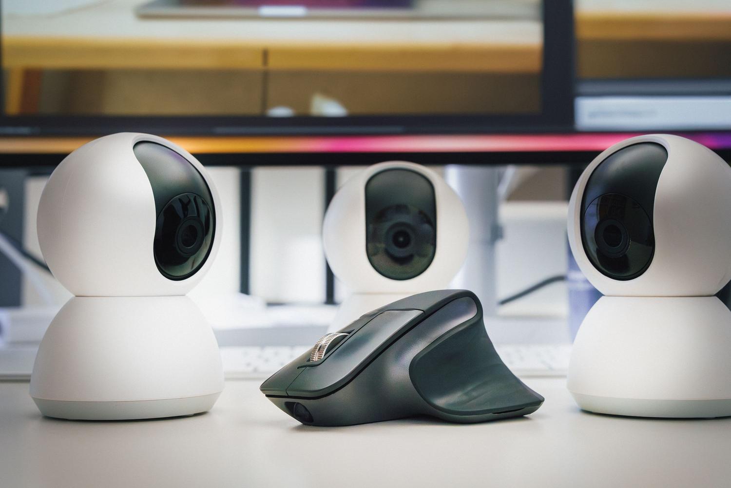 Detalle de webcams y un ratón sobre una superficie blanca, ejemplificando las herramientas de captura de imagen y control.