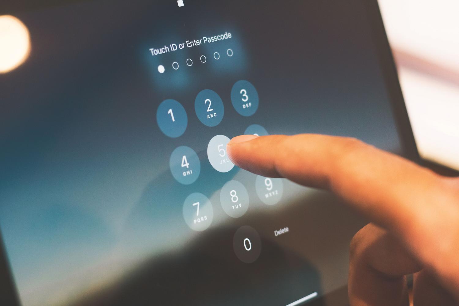 Detalle de un dedo introduciendo el código de seguridad en la pantalla de bloqueo de un dispositivo iOS.